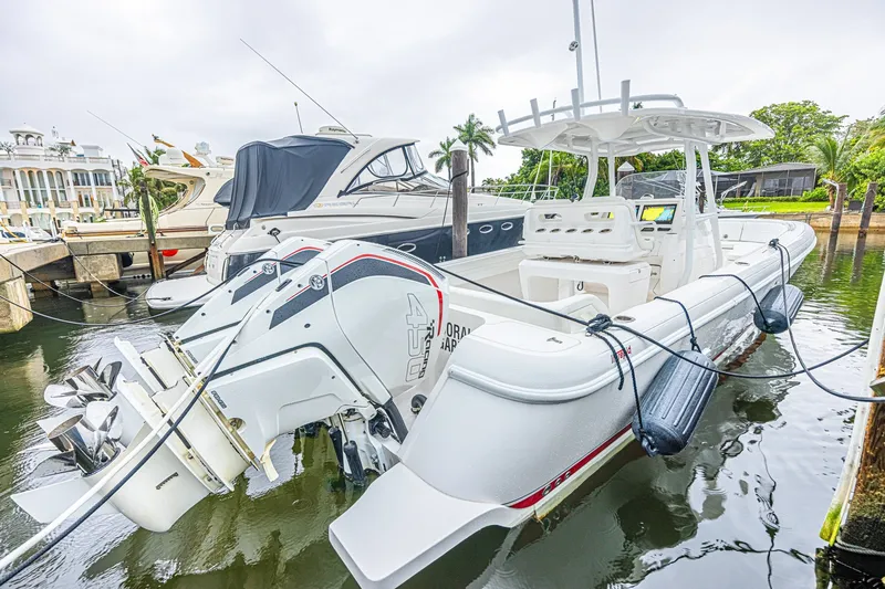 Slide: The Image of 2023 Intrepid 327 Nomad boat docked, featuring powerful outboard engines and sleek design. - 35