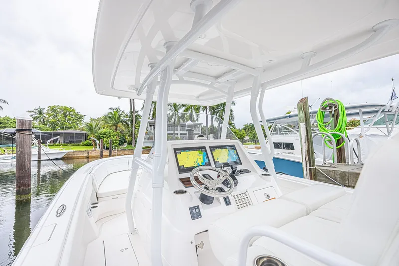 Slide: The Image of 2023 Intrepid 327 Nomad boat cockpit with modern navigation system, docked in a marina. - 7