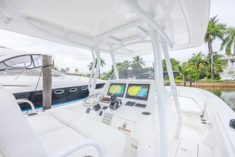 Slide: The Image of 2023 Intrepid 327 Nomad boat interior with navigation screens and white seating. - 10