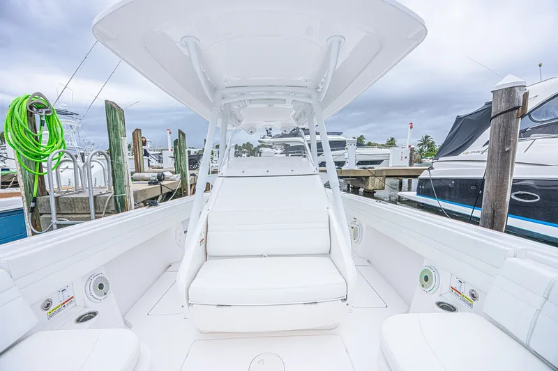 Slide: The Image of 2023 Intrepid 327 Nomad boat interior at marina, featuring sleek white seating and modern design. - 18