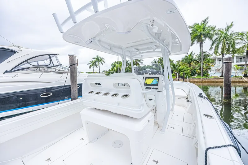 Slide: The Image of 2023 Intrepid 327 Nomad boat interior with helm, docked near palm trees. - 29