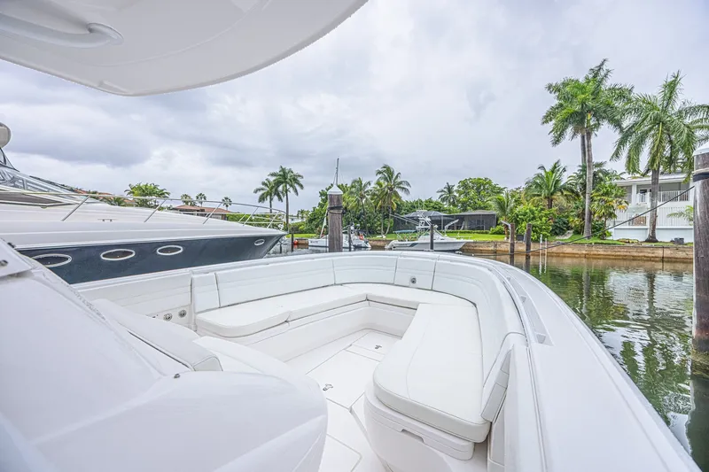 Slide: The Image of 2023 Intrepid 327 Nomad boat with spacious seating, docked near palm trees. - 22