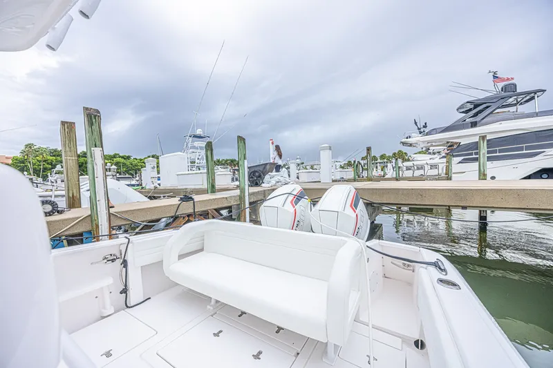 Slide: The Image of 2023 Intrepid 327 Nomad boat docked at marina with twin engines and overcast sky. - 27