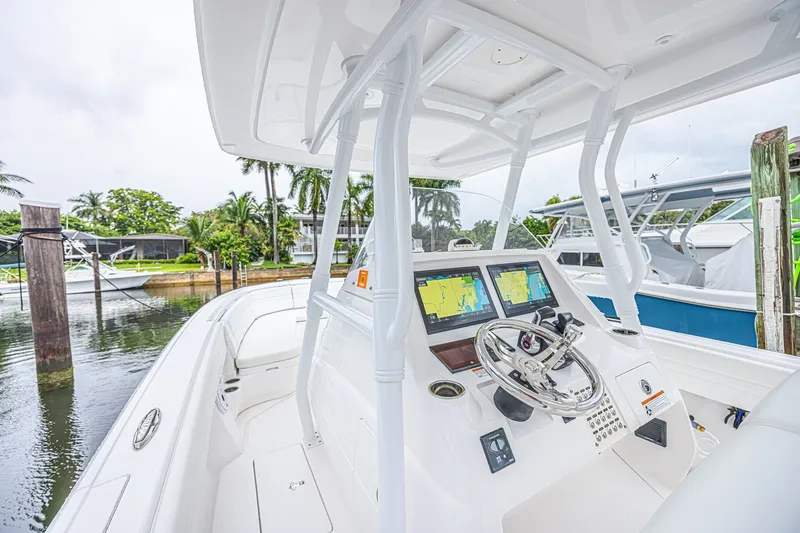 Slide: The Image of 2023 Intrepid 327 Nomad boat cockpit with modern navigation system, docked near palm trees. - 25