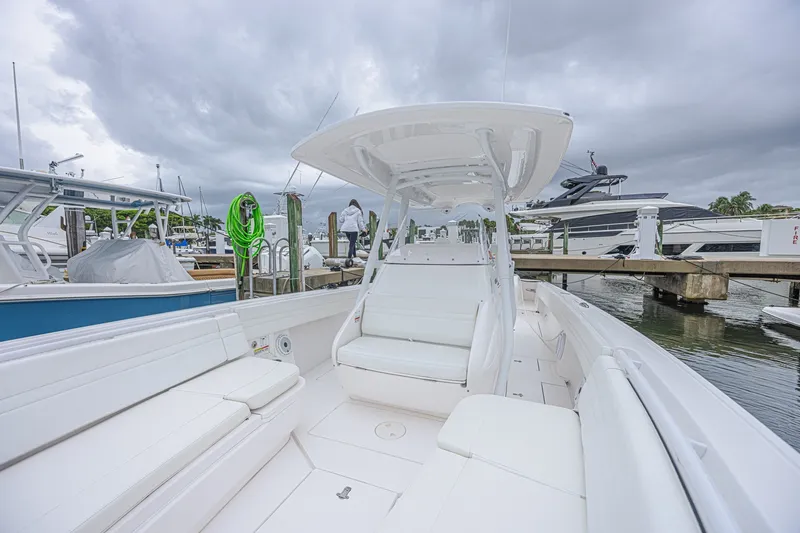 Slide: The Image of 2023 Intrepid 327 Nomad boat docked, featuring sleek white seating and modern design. - 17