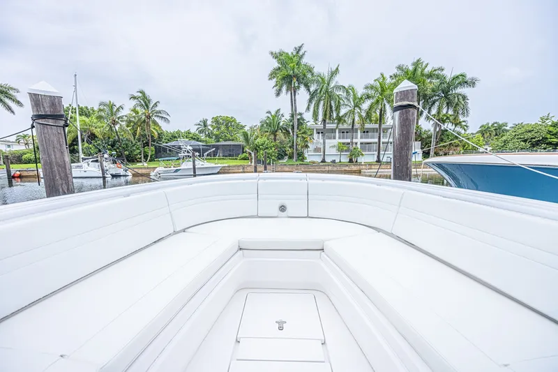 Slide: The Image of 2023 Intrepid 327 Nomad boat interior with white seating, docked near palm trees. - 19