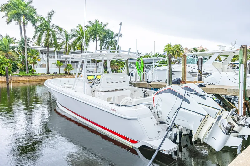 Slide: The Image of 2023 Intrepid 327 Nomad boat docked near palm trees, showcasing sleek design and powerful engines. - 2