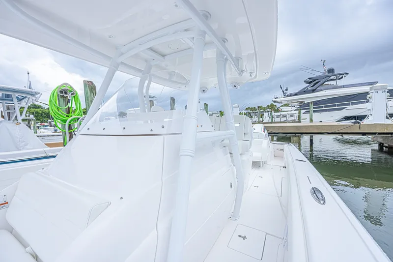 Slide: The Image of 2023 Intrepid 327 Nomad boat docked, showcasing sleek white design and spacious deck. - 20