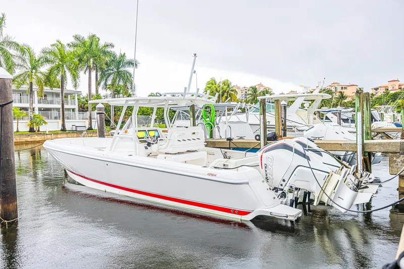 Slide: The Image of 2023 Intrepid 327 Nomad boat docked in a marina with palm trees in the background. - 1