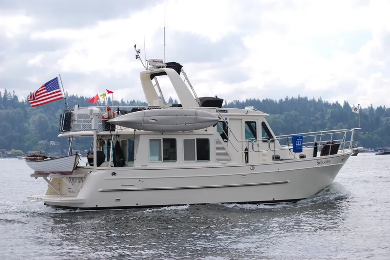 The Image of 2012 North Pacific 39 Pilothouse cruising on a scenic lake with flags and a kayak. - 0