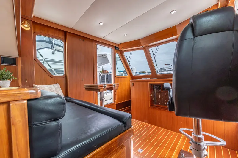 Slide: The Image of Interior of 2010 North Pacific 39 Pilothouse with wood paneling and black seating. - 15