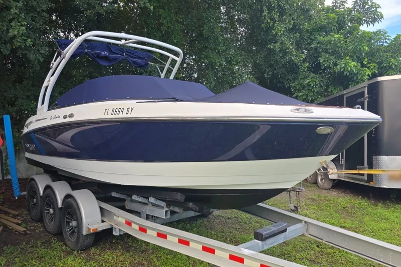 The Image of 2022 Monterey M-225 boat on trailer, covered, parked outdoors near trees. - 0