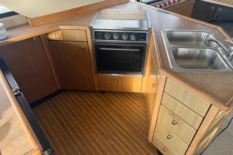 Slide: The Image of 2000 Bayliner 3988 Command Bridge Motoryacht kitchen with oven, double sink, and wooden cabinetry. - 14