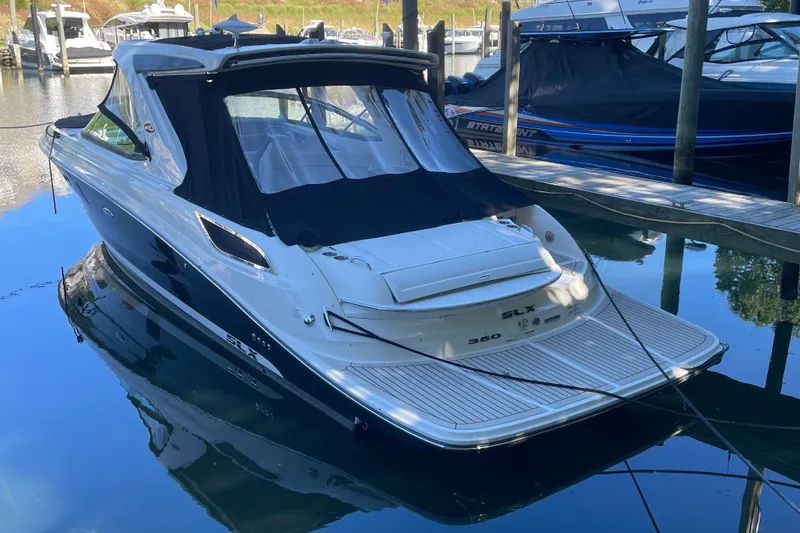 Slide: The Image of 2015 Sea Ray SLX 350 boat docked in a marina, featuring sleek design and black canopy. - 1