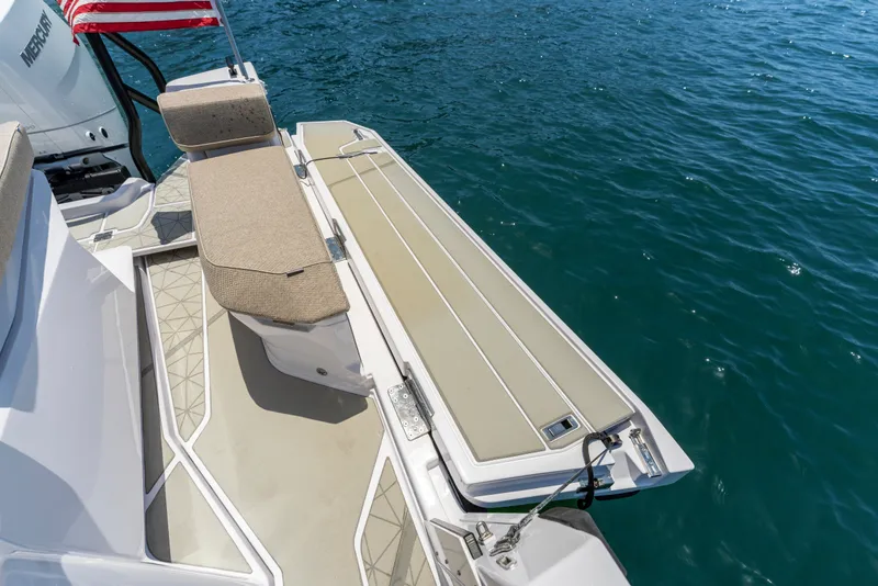 Slide: The Image of 2027 Axopar 38 Cross Cabin boat deck with seating, American flag, and ocean view. - 21
