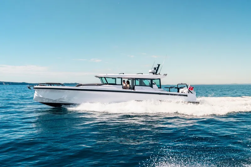 The Image of 2027 Axopar 38 Cross Cabin cruising on open water under clear blue sky. - 0