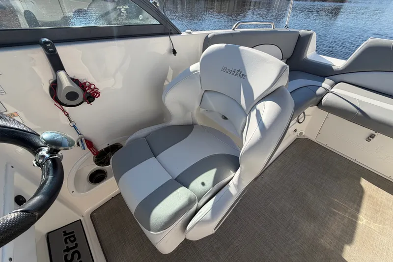 Slide: The Image of 2021 NauticStar 223 DC boat interior with steering wheel and cushioned seating. - 13