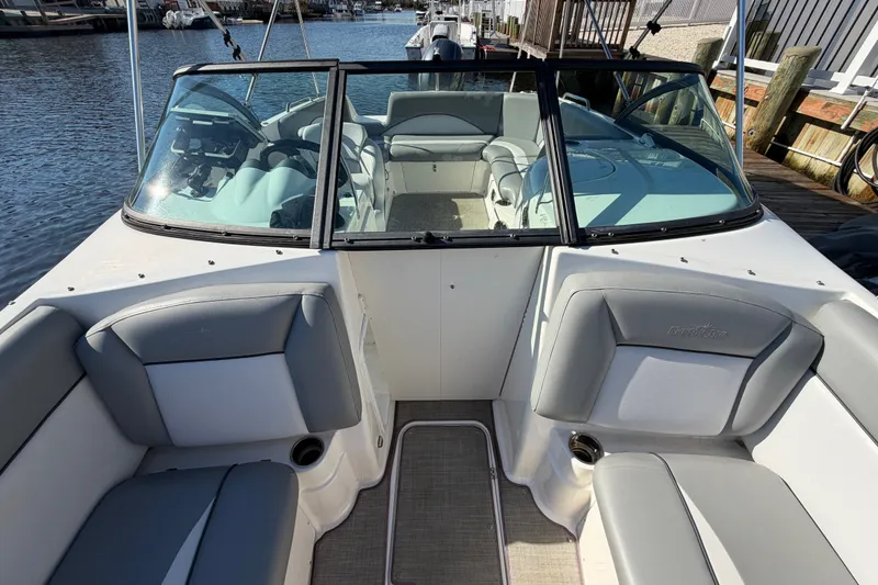 Slide: The Image of 2021 NauticStar 223 DC boat interior with gray seating, docked by the water. - 24