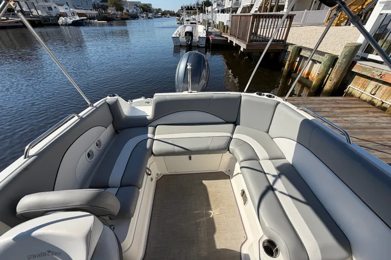 Slide: The Image of 2021 NauticStar 223 DC boat interior with gray seating, docked by a waterfront. - 11