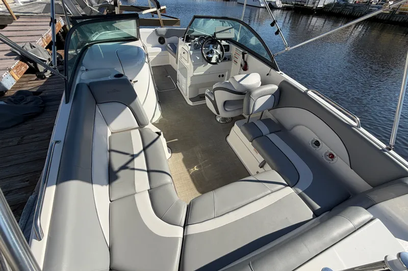 Slide: The Image of 2021 NauticStar 223 DC boat interior with spacious seating and modern helm, docked by water. - 10