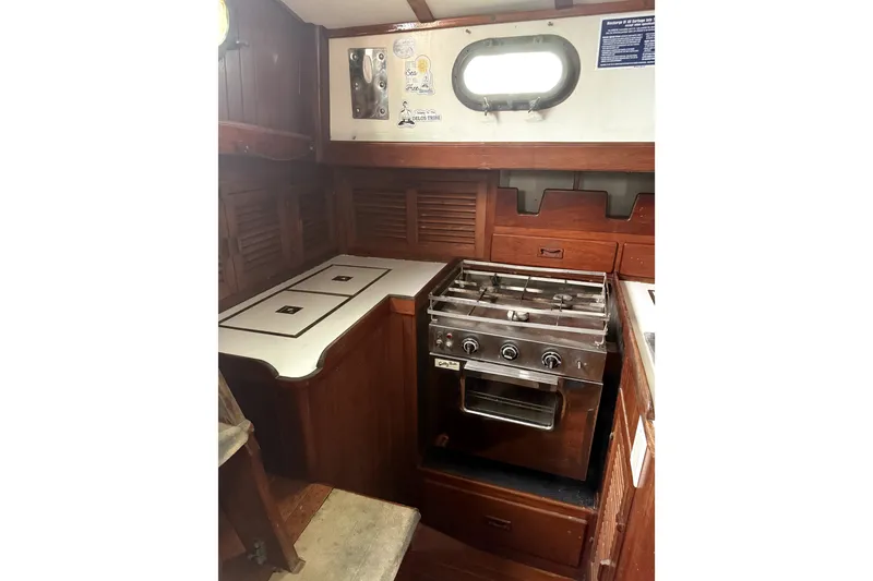 Slide: The Image of 1979 Tayana 37 yacht interior with wooden cabinetry and a compact stove. - 15
