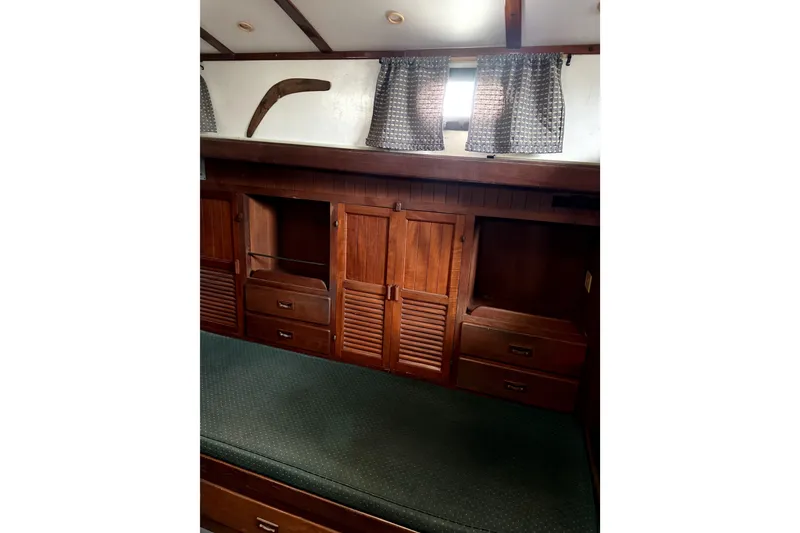 Slide: The Image of Interior of 1979 Tayana 37 sailboat with wooden cabinets and green cushioned seating. - 16