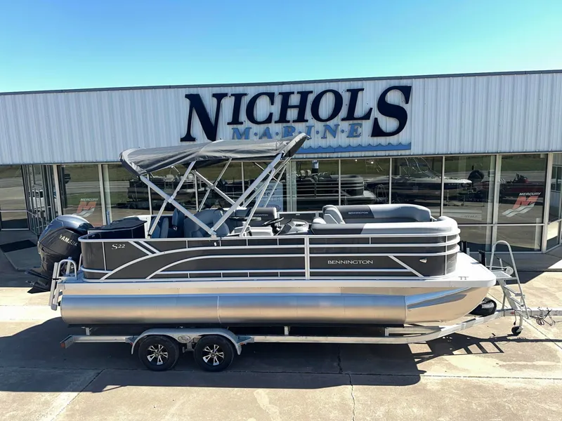 The Image of A Bennington 22 SFC pontoon boat is on a trailer in front of a building labeled "Nichols Marine." - 0