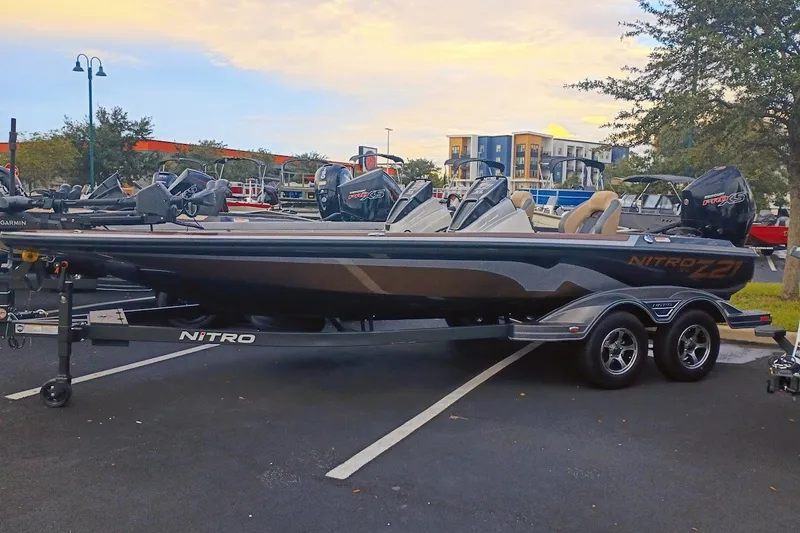 Slide: The Image of 2027 Nitro Z21 XL Pro boat on trailer in parking lot, under a cloudy sky. - 2