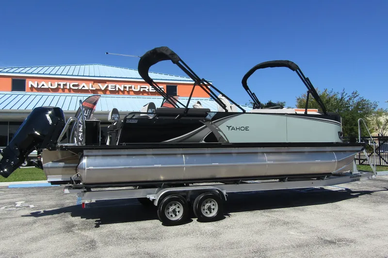 The Image of Ein moderner Pontonboot mit zwei Bimini-Tops, auf einem Anhänger vor einem Gebäude geparkt. - 0