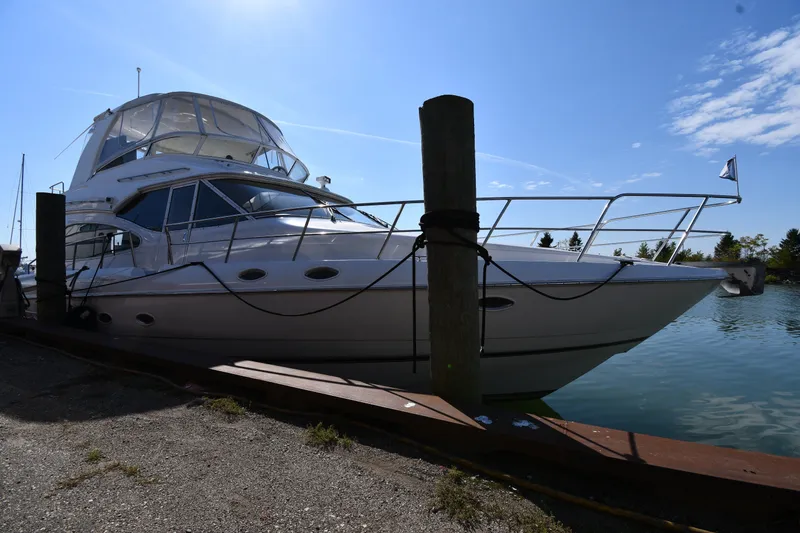 Slide: The Image of 2003 Cruisers Yachts 5000 Sedan Sport docked by the water on a sunny day. - 4