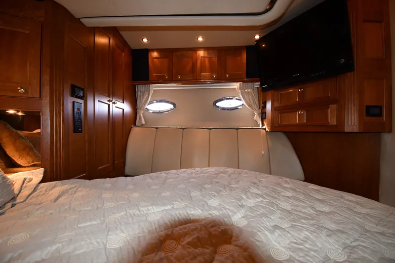 Slide: The Image of Luxurious interior of 2003 Cruisers Yachts 5000 Sedan Sport with wood cabinetry and cozy bedding. - 49