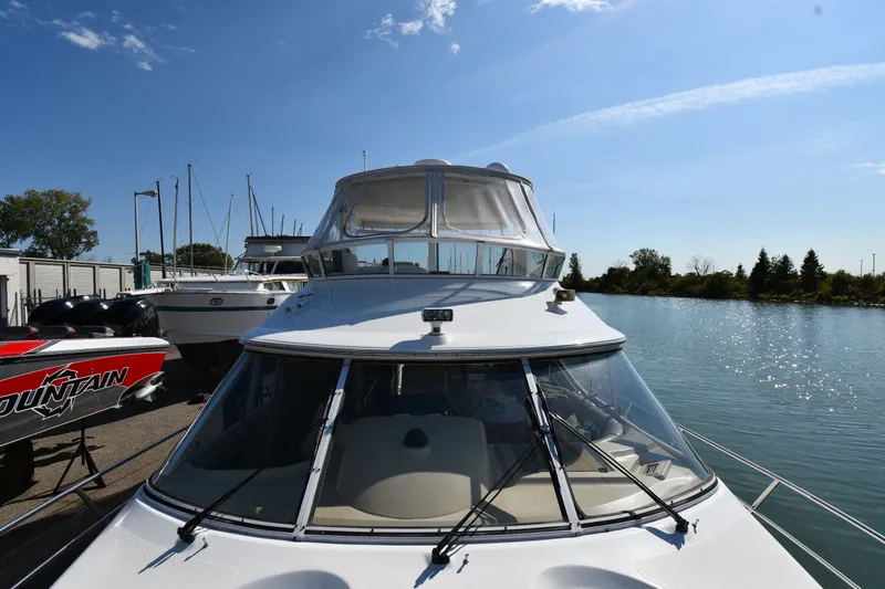 Slide: The Image of 2003 Cruisers Yachts 5000 Sedan Sport docked by a serene waterfront. - 11
