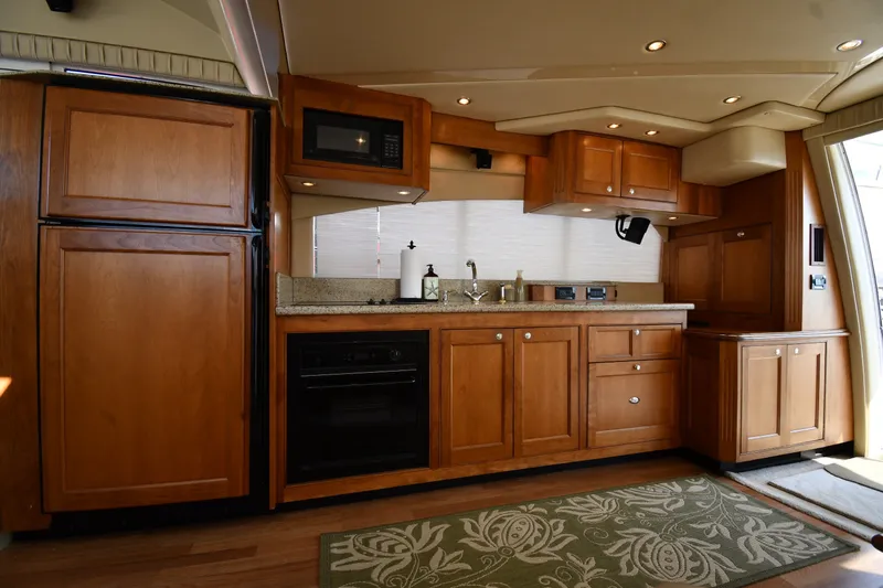 Slide: The Image of Luxurious kitchen interior of 2003 Cruisers Yachts 5000 Sedan Sport with wooden cabinetry. - 61