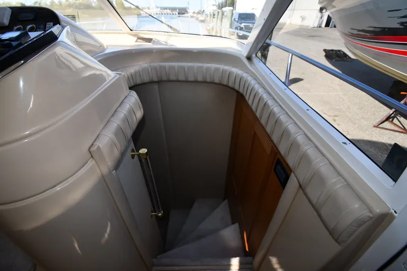 Slide: The Image of Interior staircase of 2003 Cruisers Yachts 5000 Sedan Sport, featuring plush seating and wooden door. - 35