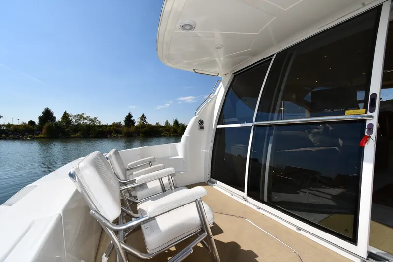 Slide: The Image of 2003 Cruisers Yachts 5000 Sedan Sport deck with chairs overlooking serene water. - 16