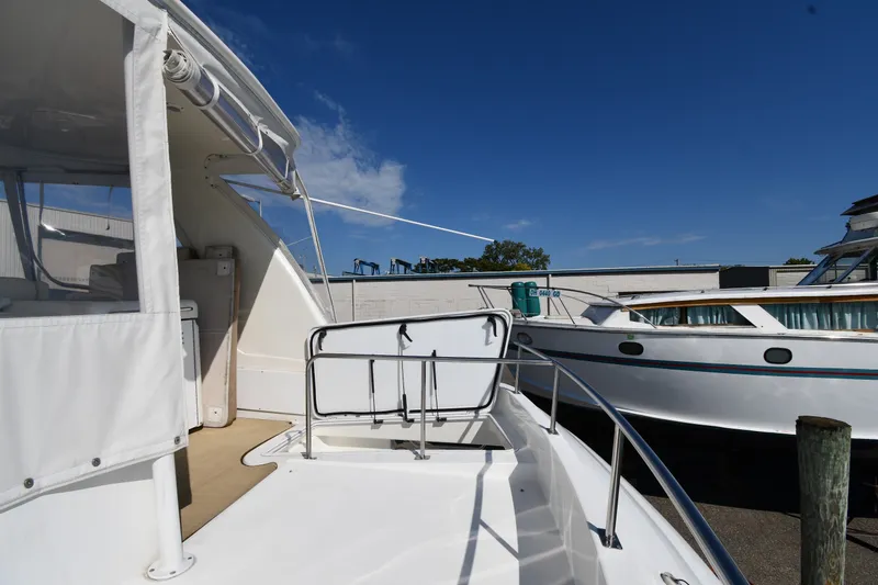 Slide: The Image of 2003 Cruisers Yachts 5000 Sedan Sport docked, showcasing deck and railing under clear blue sky. - 20