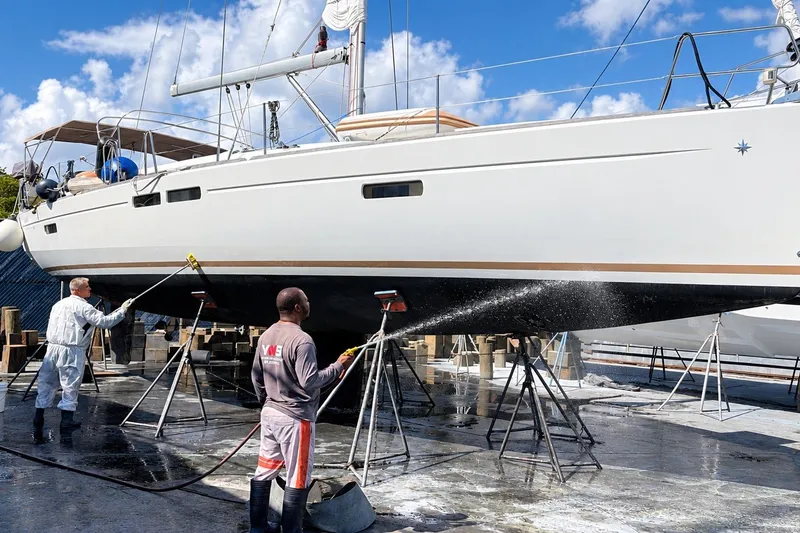 The Image of Workers cleaning a 2016 Jeanneau Sun Odyssey 469 sailboat on stands. - 0