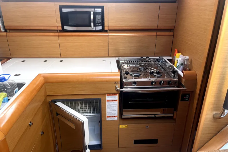 Slide: The Image of 2016 Jeanneau Sun Odyssey 469 yacht kitchen with stove, microwave, and fridge. - 13