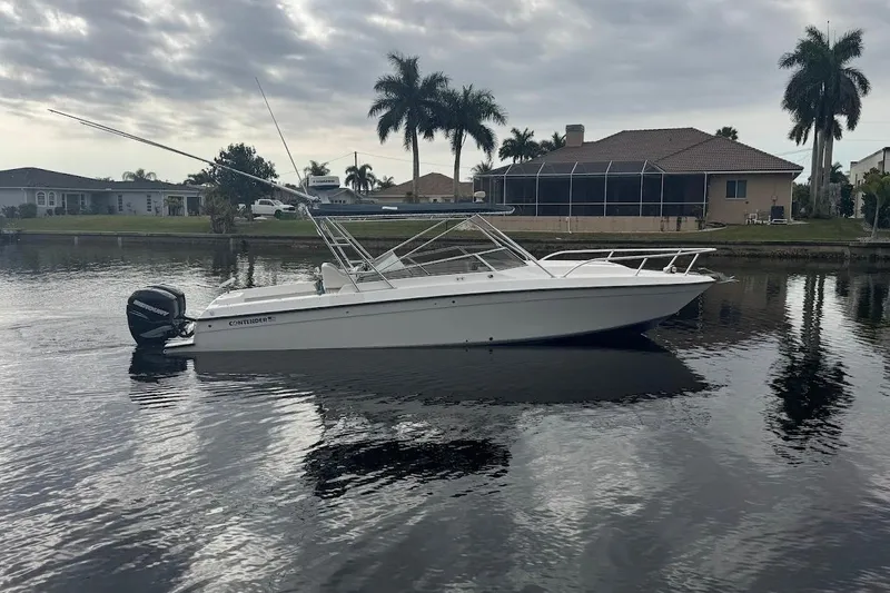 Slide: The Image of 2001 Contender 35 Side Console boat on calm water, with palm trees and houses in the background. - 1