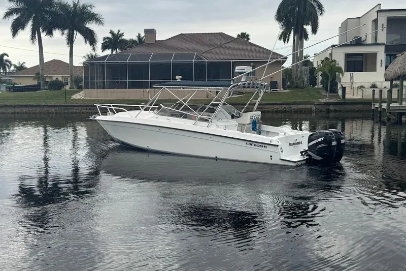 Slide: The Image of 2001 Contender 35 Side Console boat on calm water near waterfront homes and palm trees. - 4