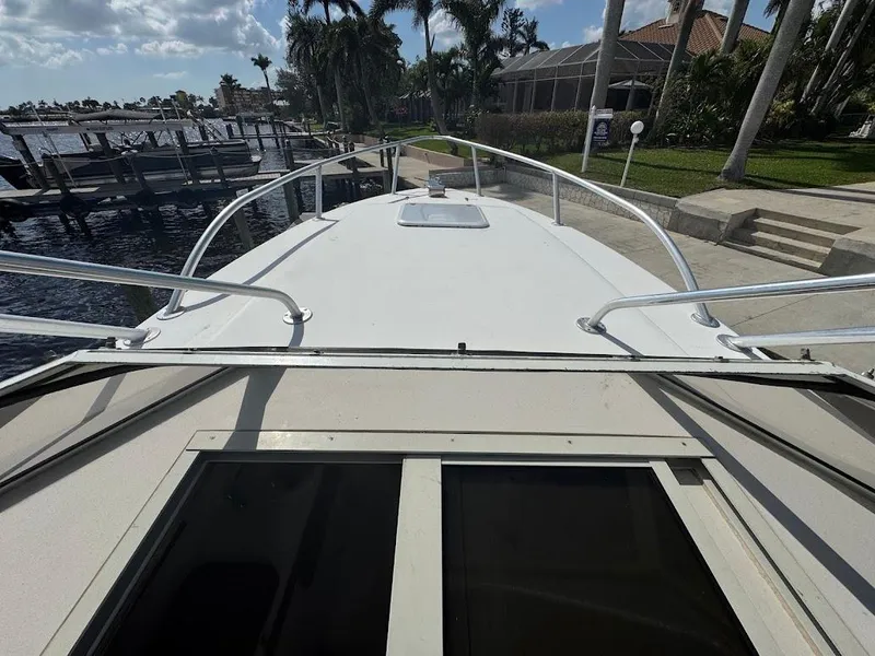 Slide: The Image of 2001 Contender 35 Side Console boat docked near palm trees and waterfront homes. - 31