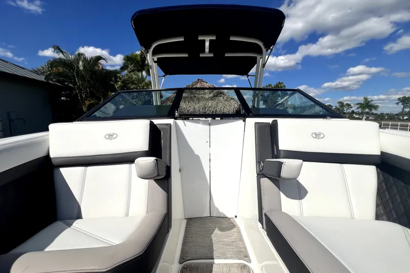 Slide: The Image of 2022 Cobalt R6 Outboard boat interior with white seating and blue canopy under a clear sky. - 75