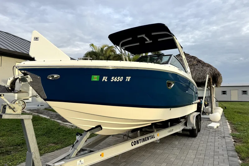 Slide: The Image of 2022 Cobalt R6 Outboard boat on trailer, blue and white, parked on paved driveway. - 2