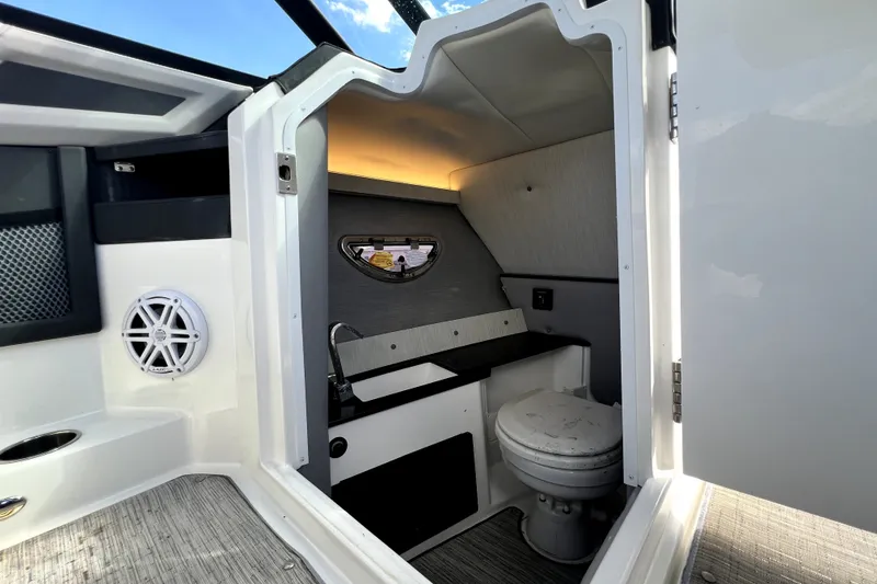 Slide: The Image of Interior of 2022 Cobalt R6 Outboard boat featuring a compact bathroom with toilet and sink. - 90