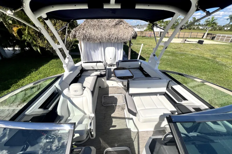 Slide: The Image of 2022 Cobalt R6 Outboard boat interior with white seating and canopy, set in a lush outdoor environment. - 41
