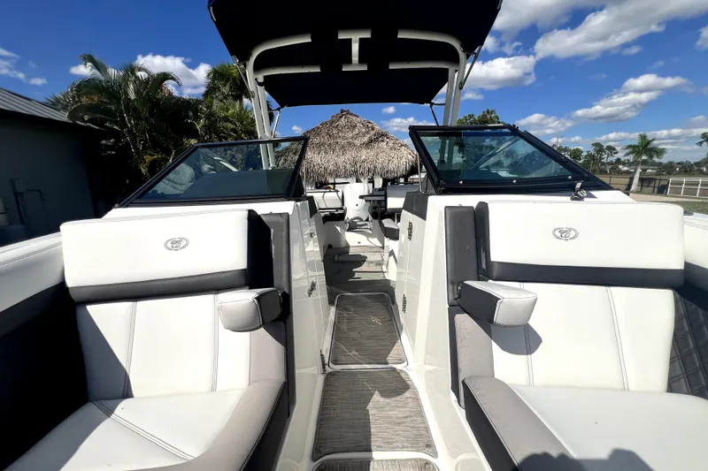 Slide: The Image of 2022 Cobalt R6 Outboard boat interior with white seating and open deck under blue sky. - 76