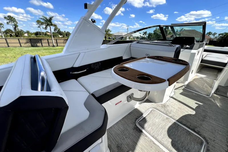 Slide: The Image of 2022 Cobalt R6 Outboard boat interior with seating and table, under a clear blue sky. - 99