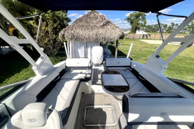 Slide: The Image of 2022 Cobalt R6 Outboard boat interior with seating and table, set in a lush outdoor environment. - 38