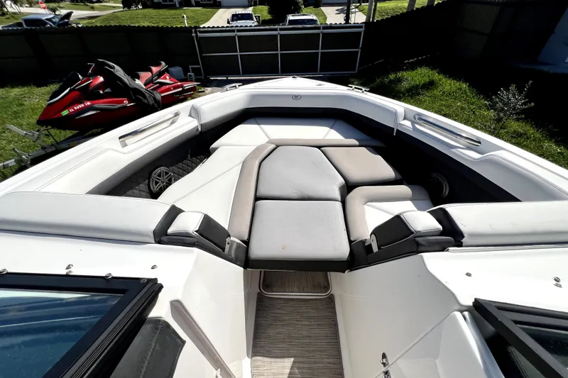 Slide: The Image of 2022 Cobalt R6 Outboard boat interior with cushioned seating and nearby jet skis. - 87