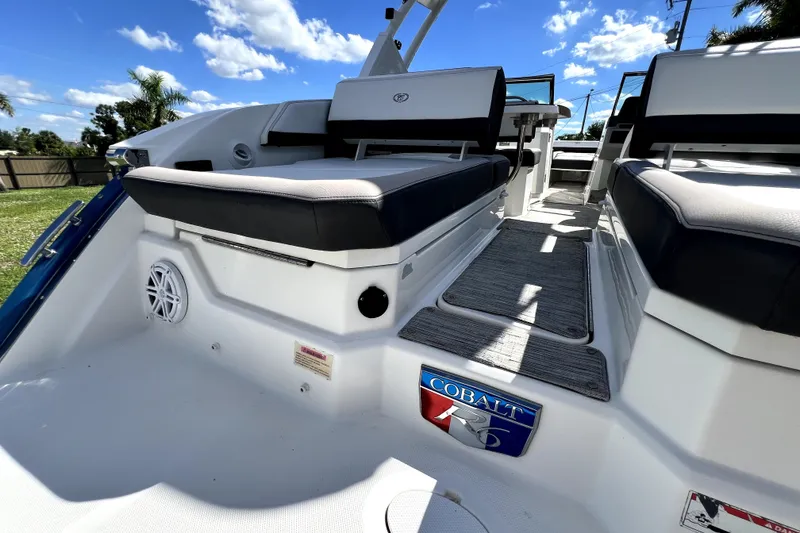 Slide: The Image of 2022 Cobalt R6 Outboard boat interior with cushioned seating and sleek design under a blue sky. - 56